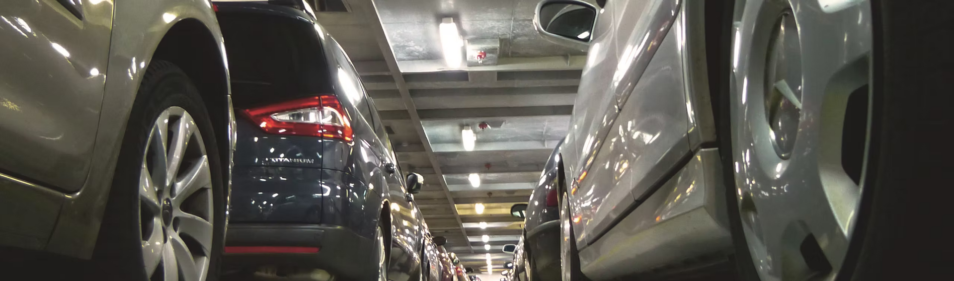A row of cars are parked in a parking garage.