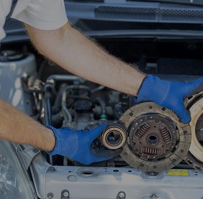 A man wearing blue gloves is working on a car engine.