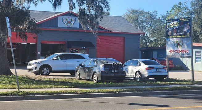 A group of cars are parked in front of a building.