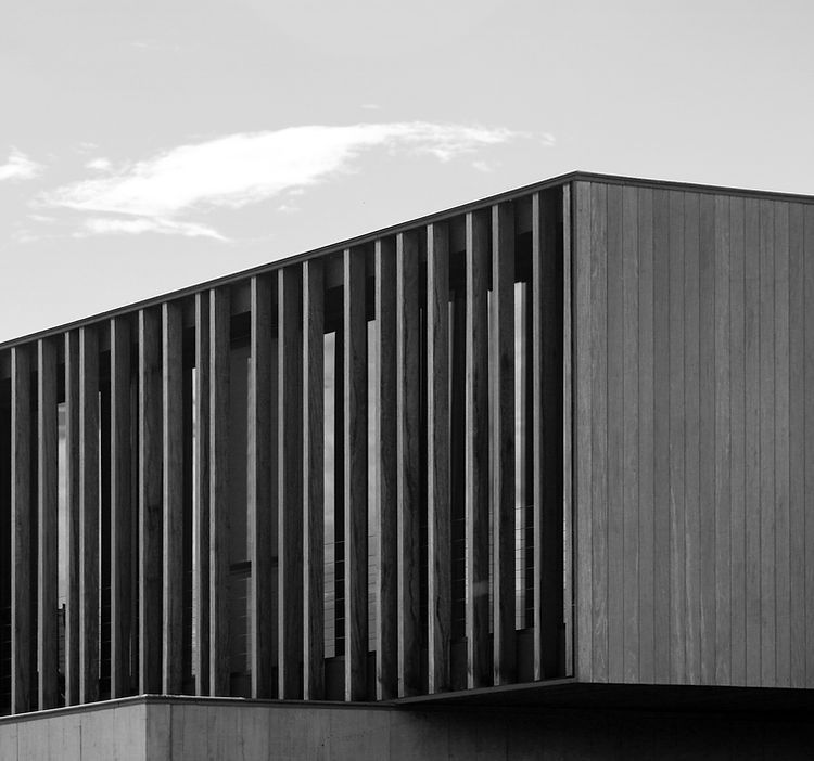 A black and white photo of a building with wooden slats on the side.