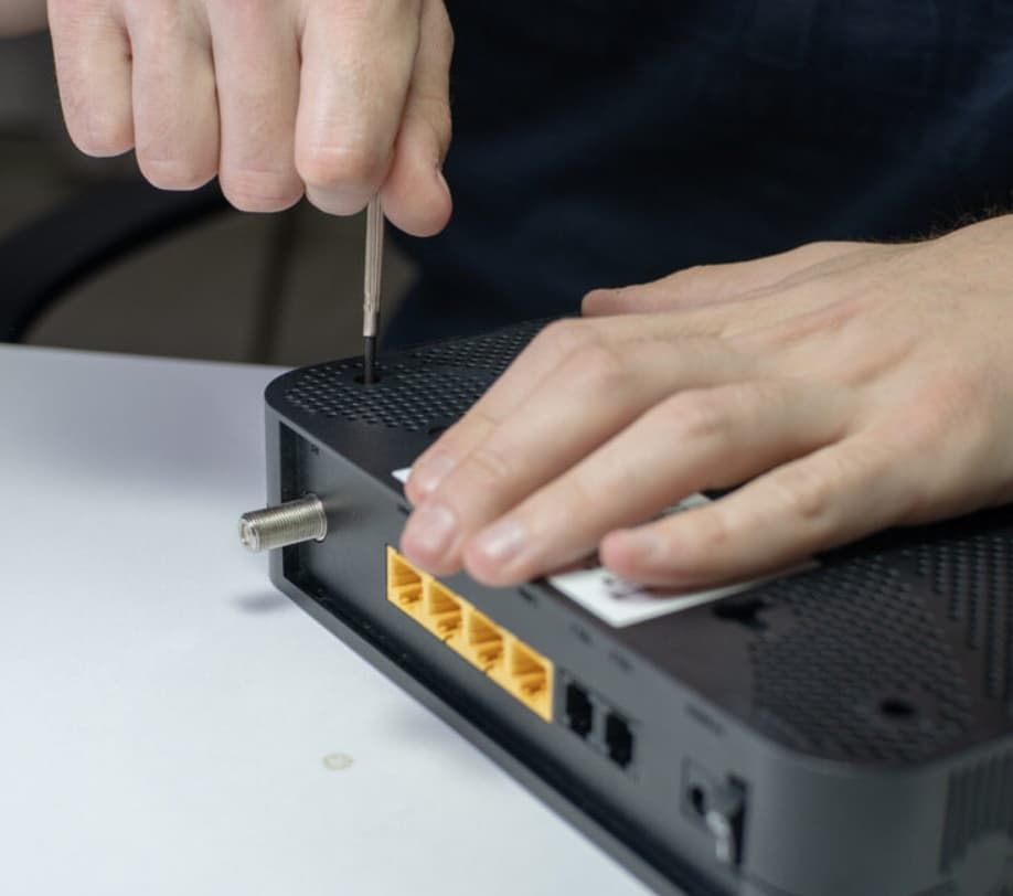 Hands Using A Screwdriver To Open A Black Router, Likely For Repair Or Modification — Fry Electrical In Budgewoi, NSW