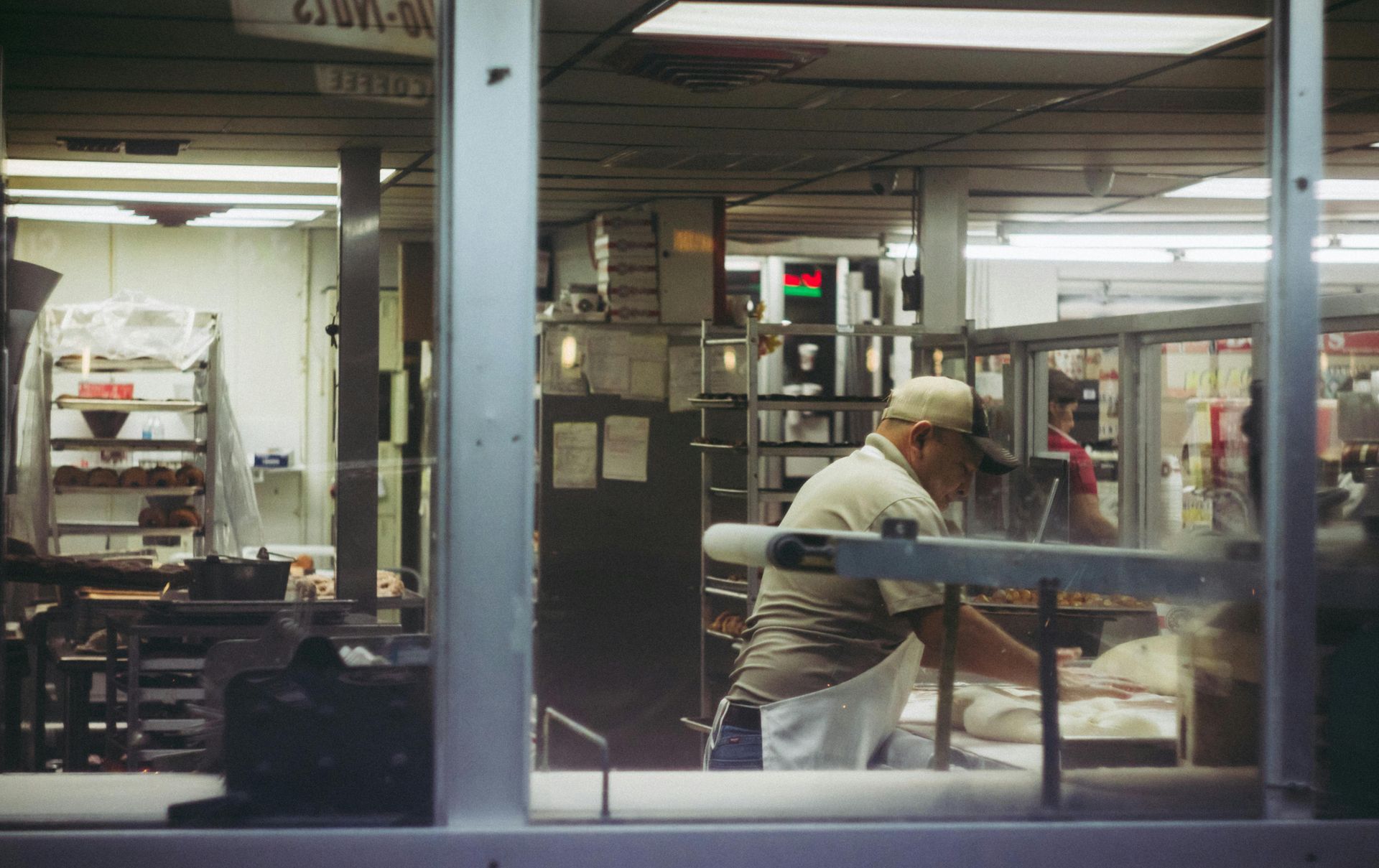 A man is standing in a kitchen behind a glass door.