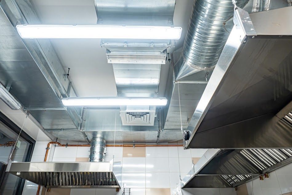 A kitchen with a lot of stainless steel appliances hanging from the ceiling.