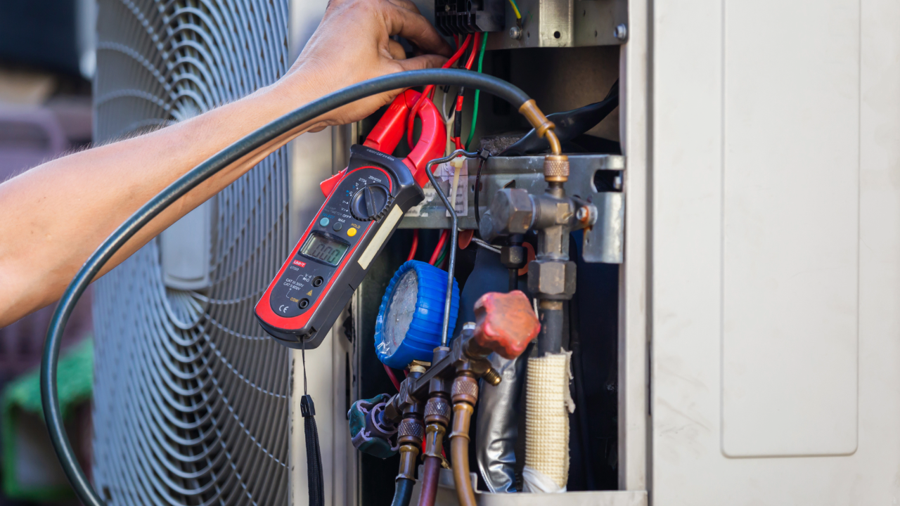 A man is working on an air conditioner with a clamp.