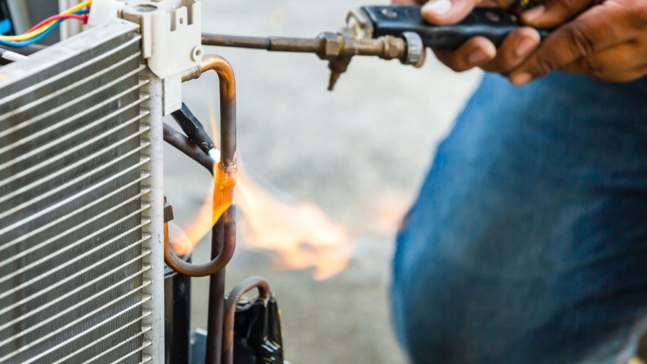 A man is welding a pipe with a torch.