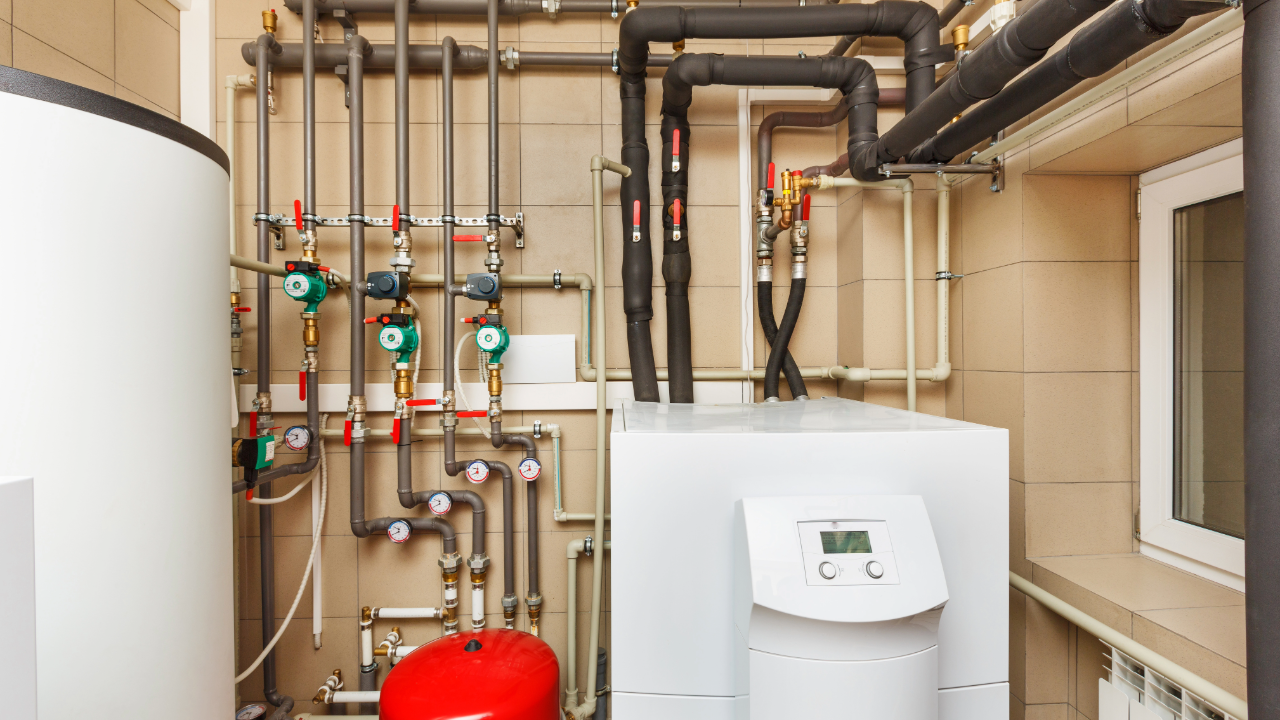 A room with a boiler and pipes in it.