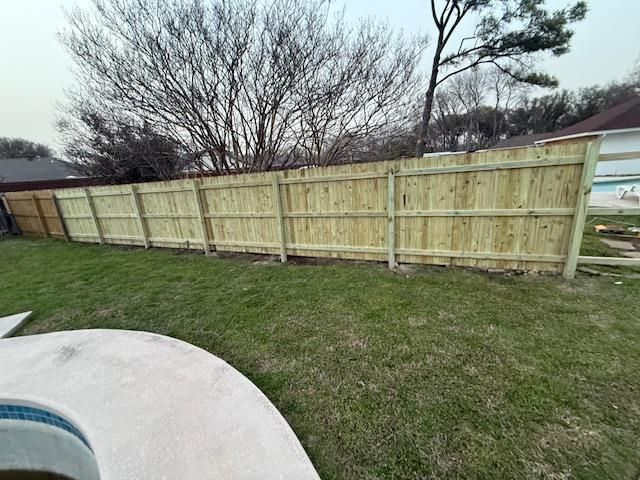 A man is working on a fence in front of a house.