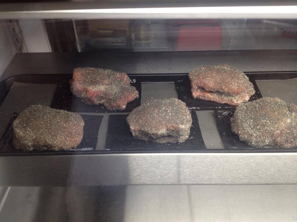Four pieces of meat are sitting on a tray in an oven.