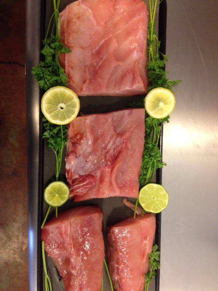 A tray of meat with lemons and parsley on it