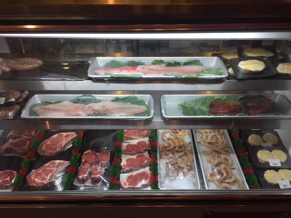 A display case filled with a variety of meats and vegetables.
