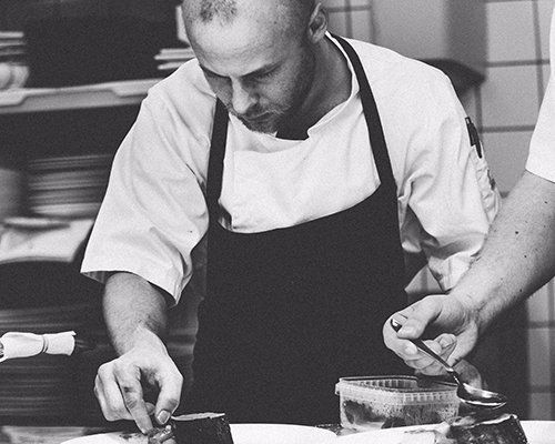 A man in an apron is preparing food in a kitchen
