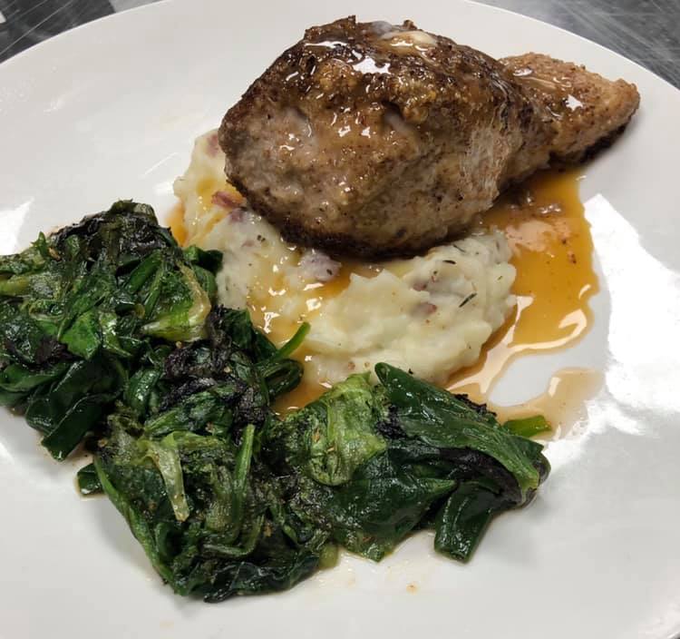 A white plate topped with meat mashed potatoes and spinach