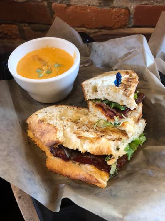 A sandwich and a bowl of soup are on a table.