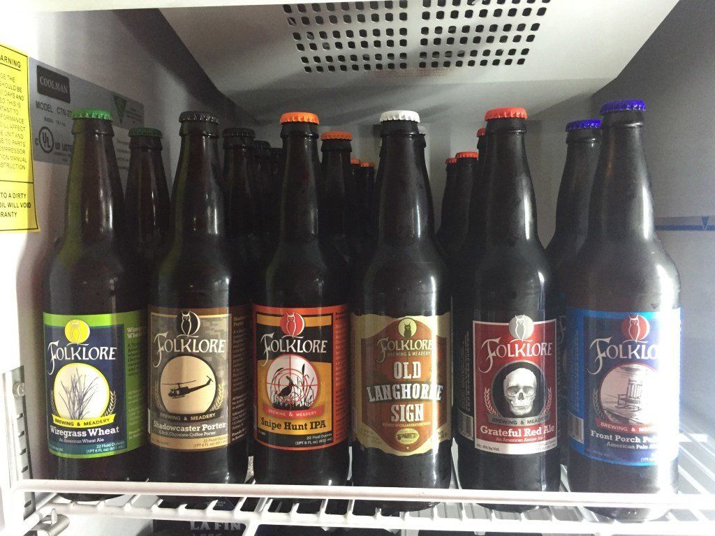 Several bottles of beer are lined up on a shelf