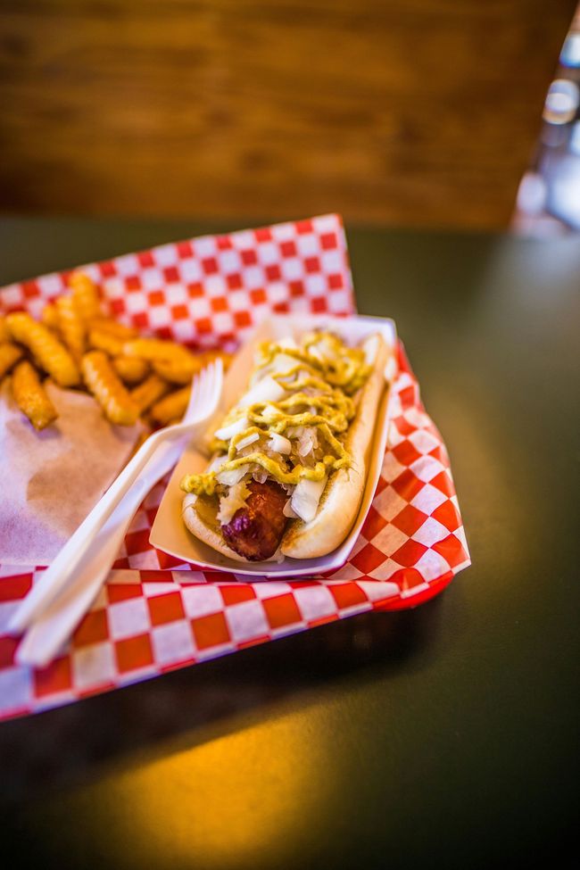 A hot dog and french fries on a checkered paper tray on a table.