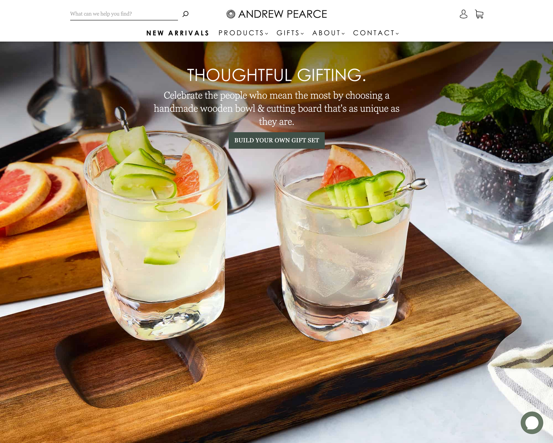 Two shot glasses with a cucumber garnish on a wooden cutting board