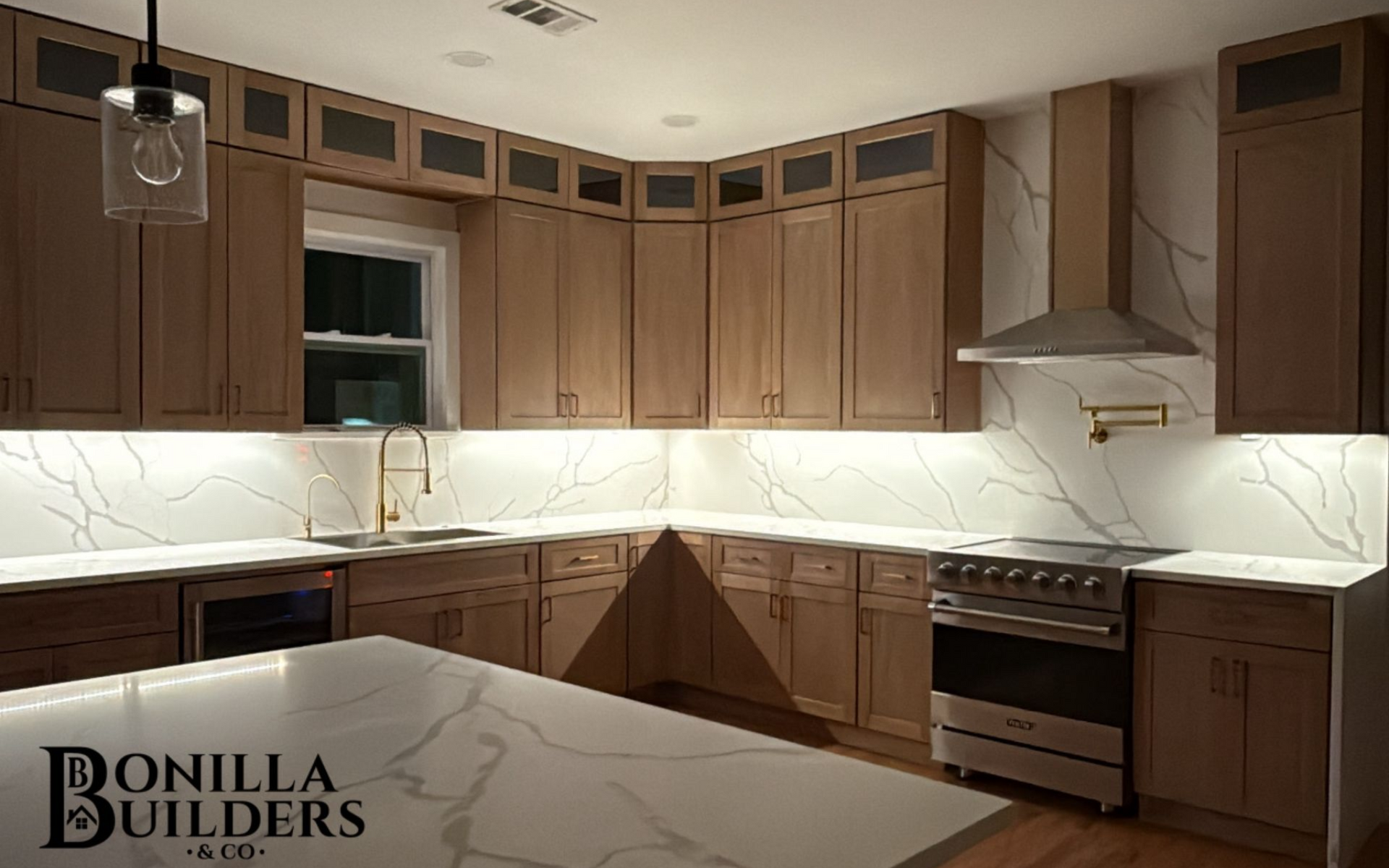 Modern kitchen with light wood cabinets, white countertops, and stainless steel appliances.