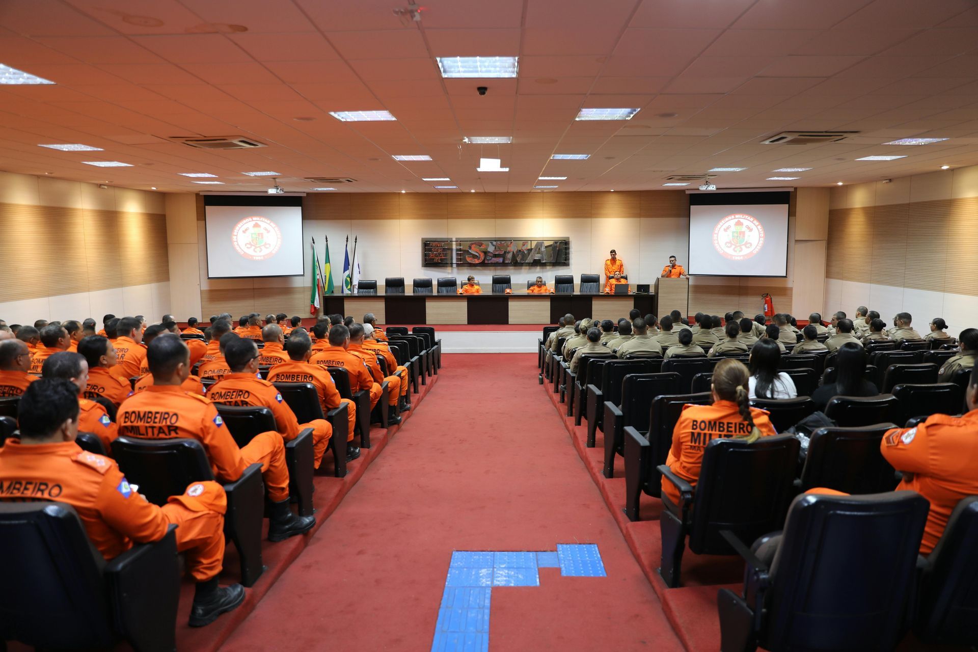 A professional presenting to an audience in a bright, modern classroom or conference room setting.