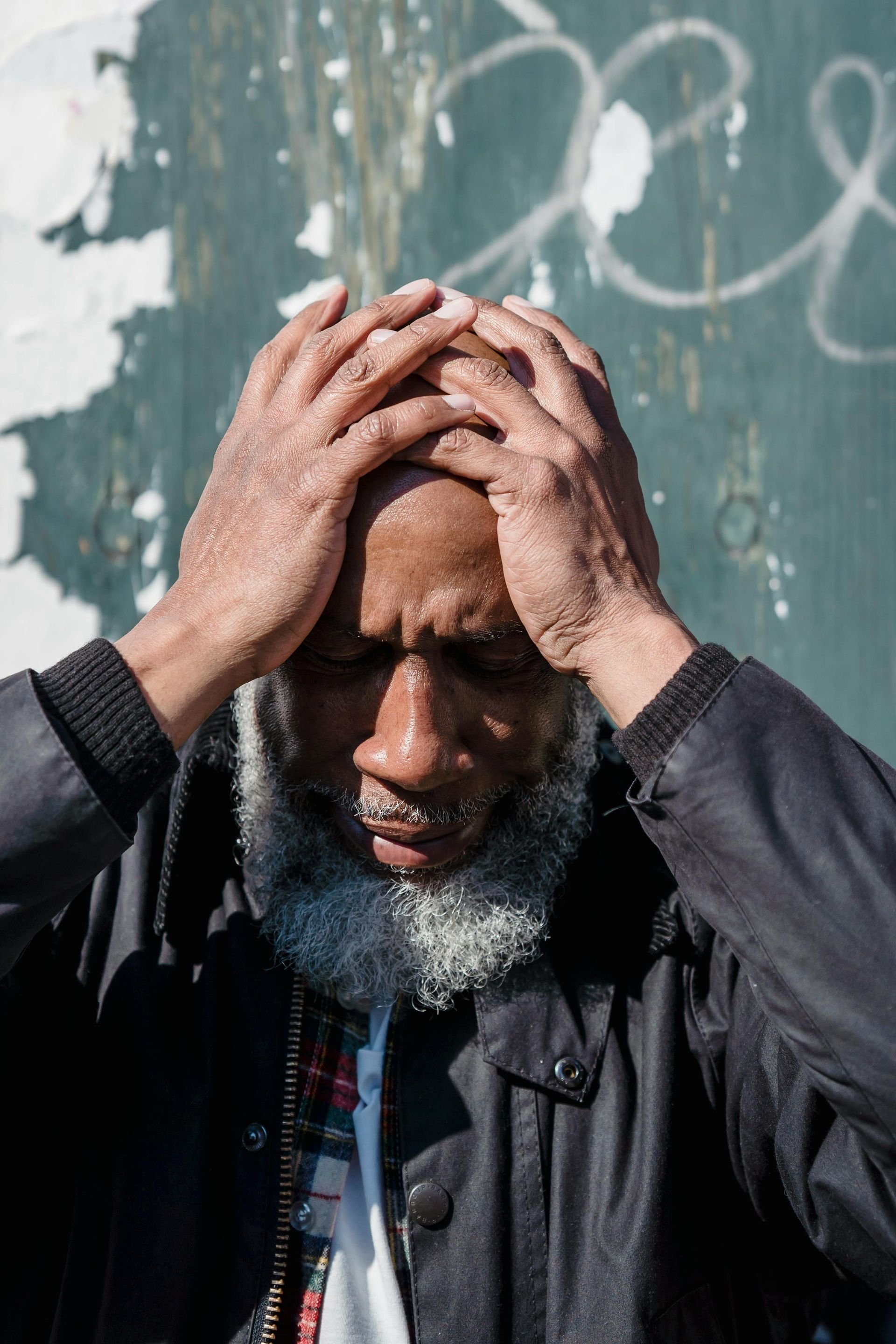 A hand in a tan sleeve holds out a set of keys toward another outstretched hand against a neutral gray background.