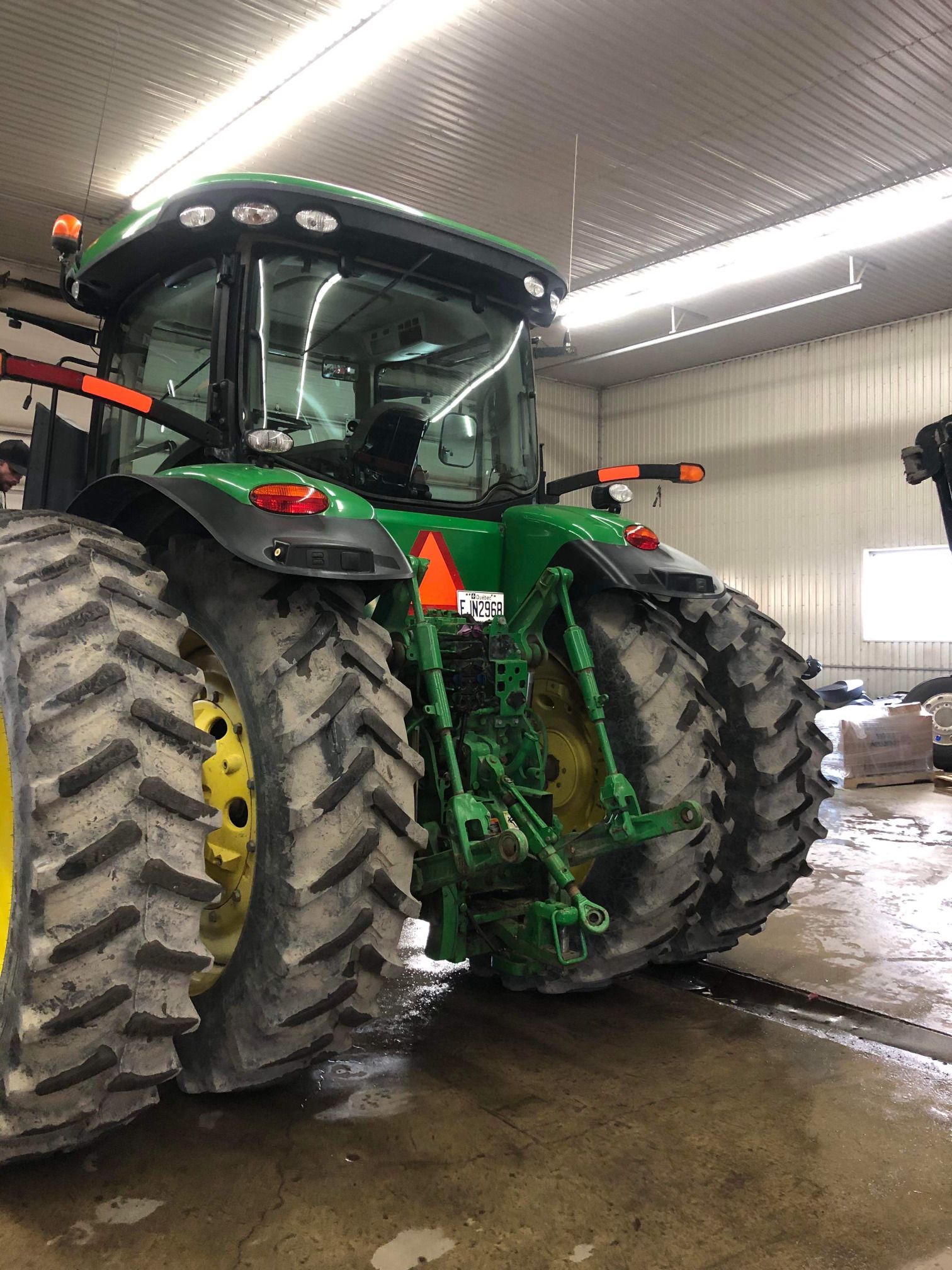 Un tracteur John Deere vert est garé dans un garage.