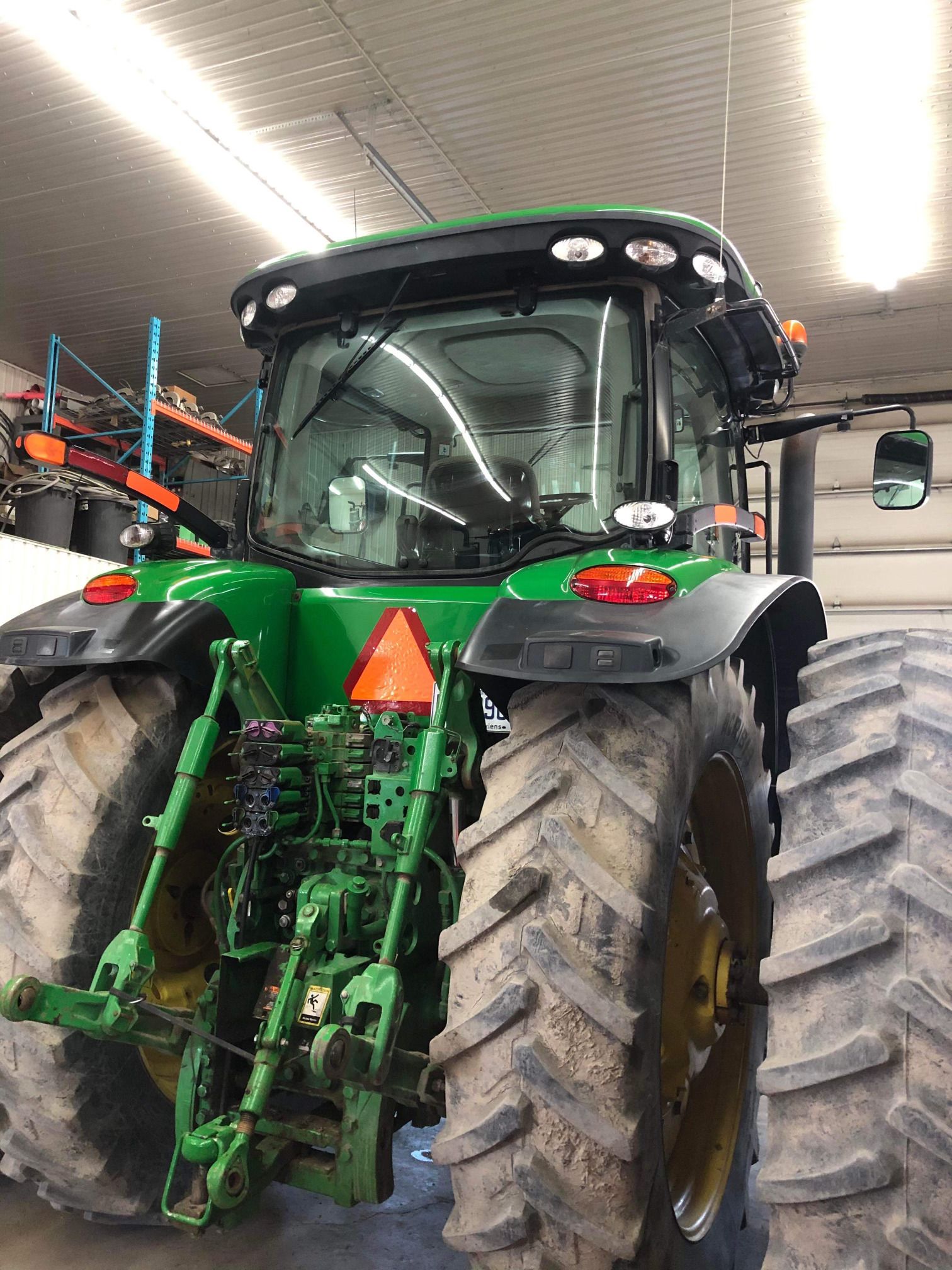 Un tracteur John Deere vert est garé dans un garage.