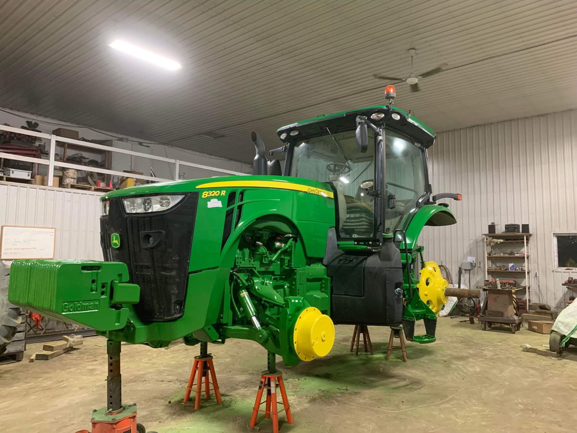 Un tracteur John Deere vert est en réparation dans un garage.