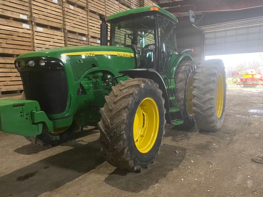 Un tracteur John Deere vert et jaune est garé dans un garage.