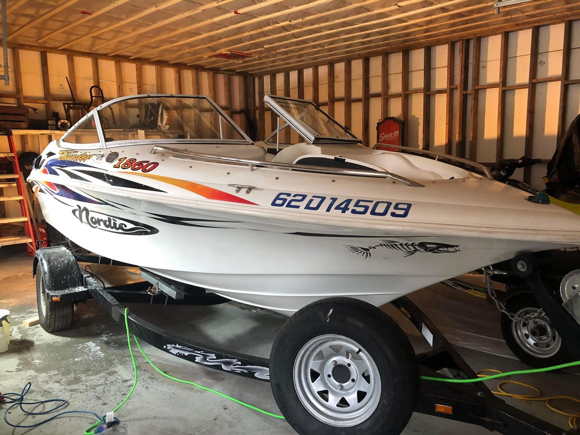 Un bateau blanc portant la plaque d'immatriculation 62014509 est garé dans un garage.
