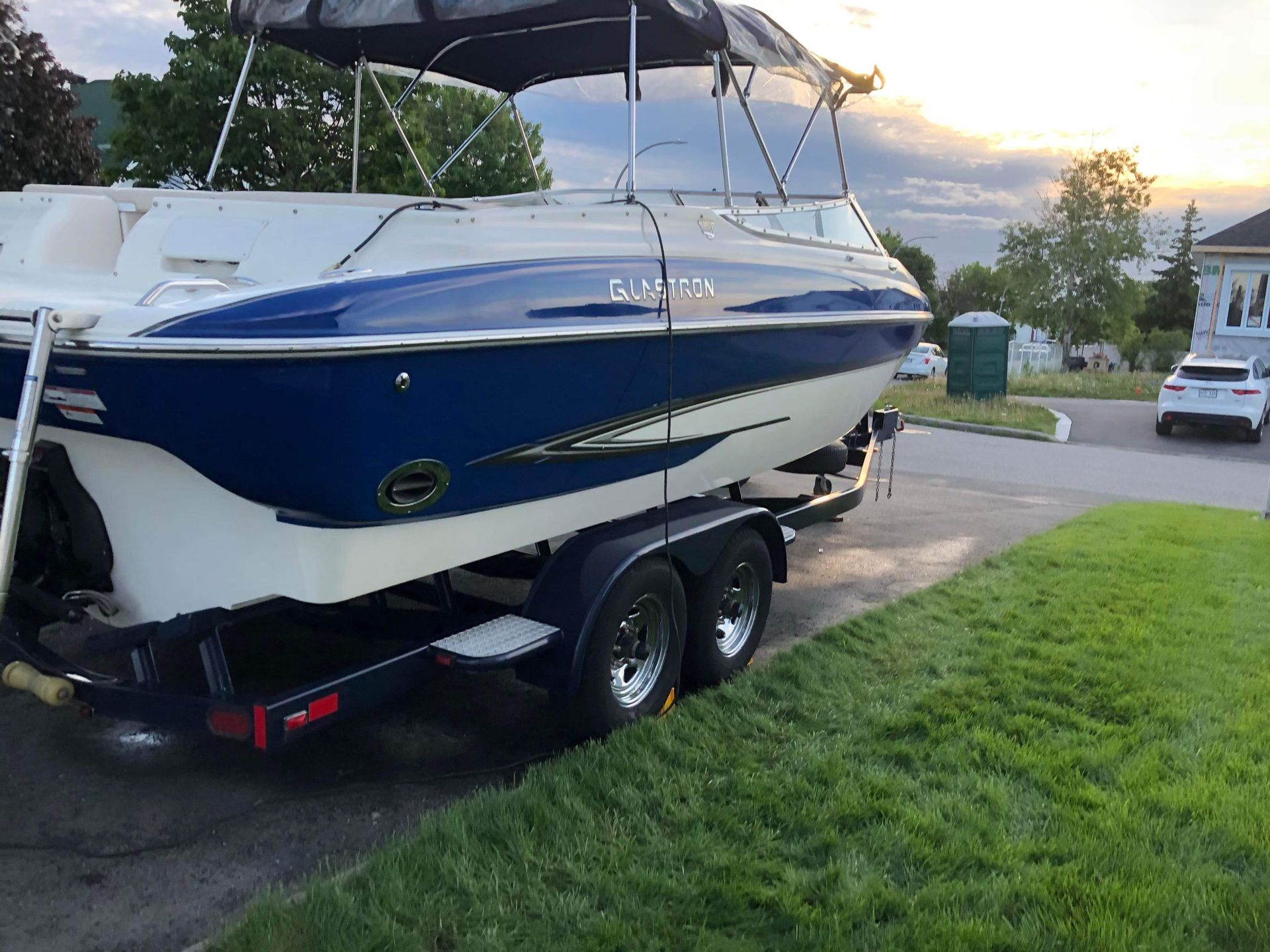 Un bateau bleu et blanc est garé sur une remorque dans une allée.