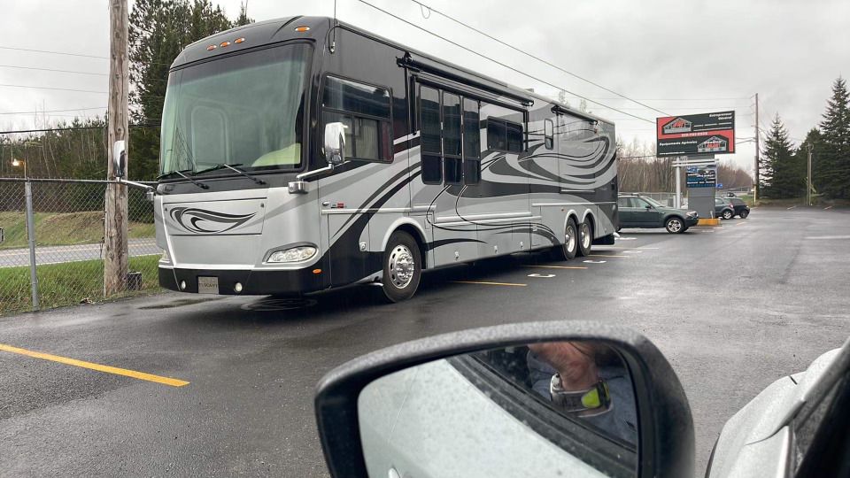 Un grand camping-car est garé au bord de la route dans un parking.