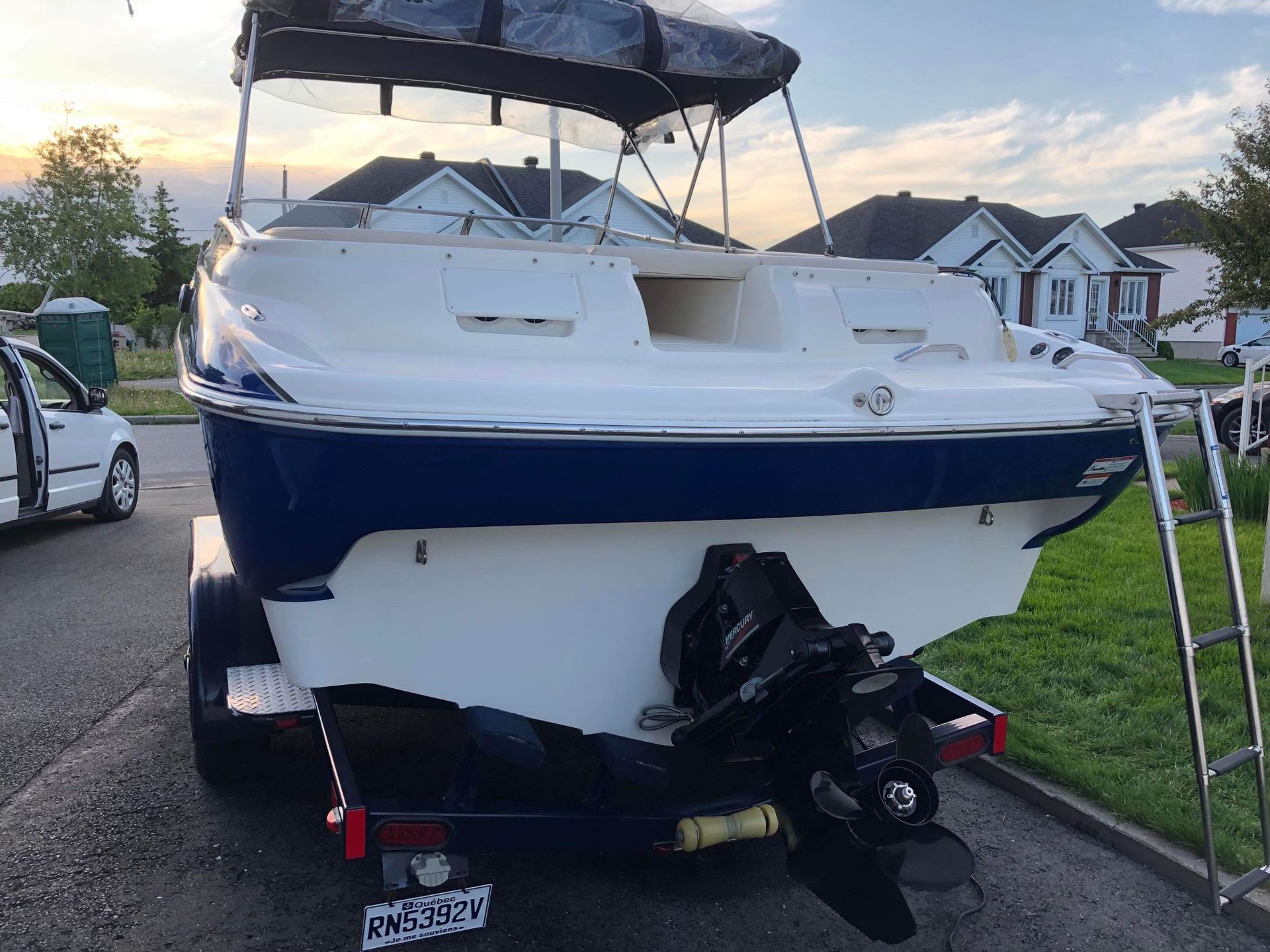 Un bateau est sur une remorque garée au bord de la route.