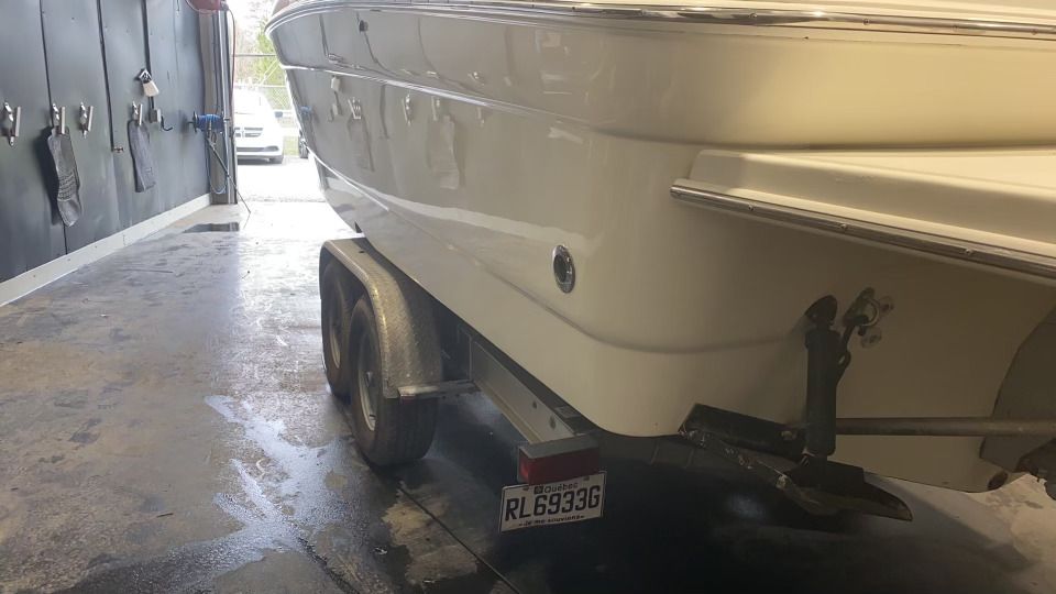 Un bateau blanc est posé sur une remorque dans un garage.