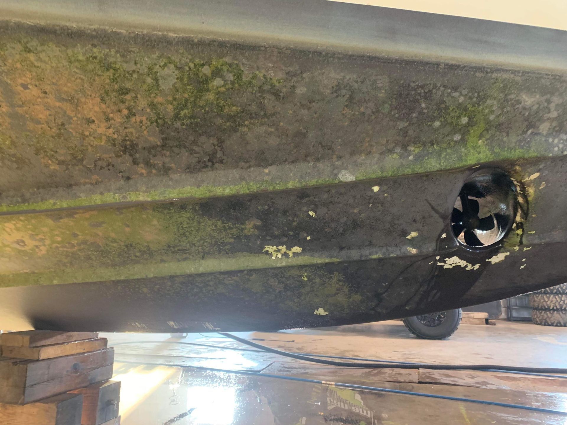 Un bateau avec une hélice manquante se trouve dans un garage.