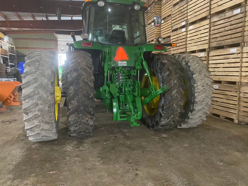 Un tracteur John Deere vert est garé dans un entrepôt.