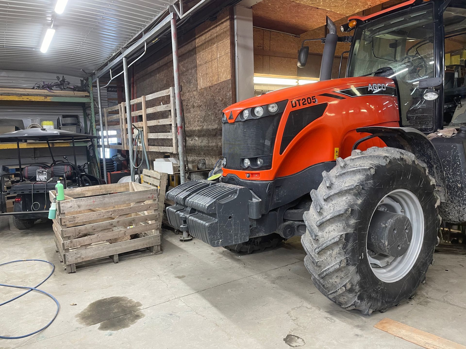 Un gros tracteur orange est garé dans un garage.