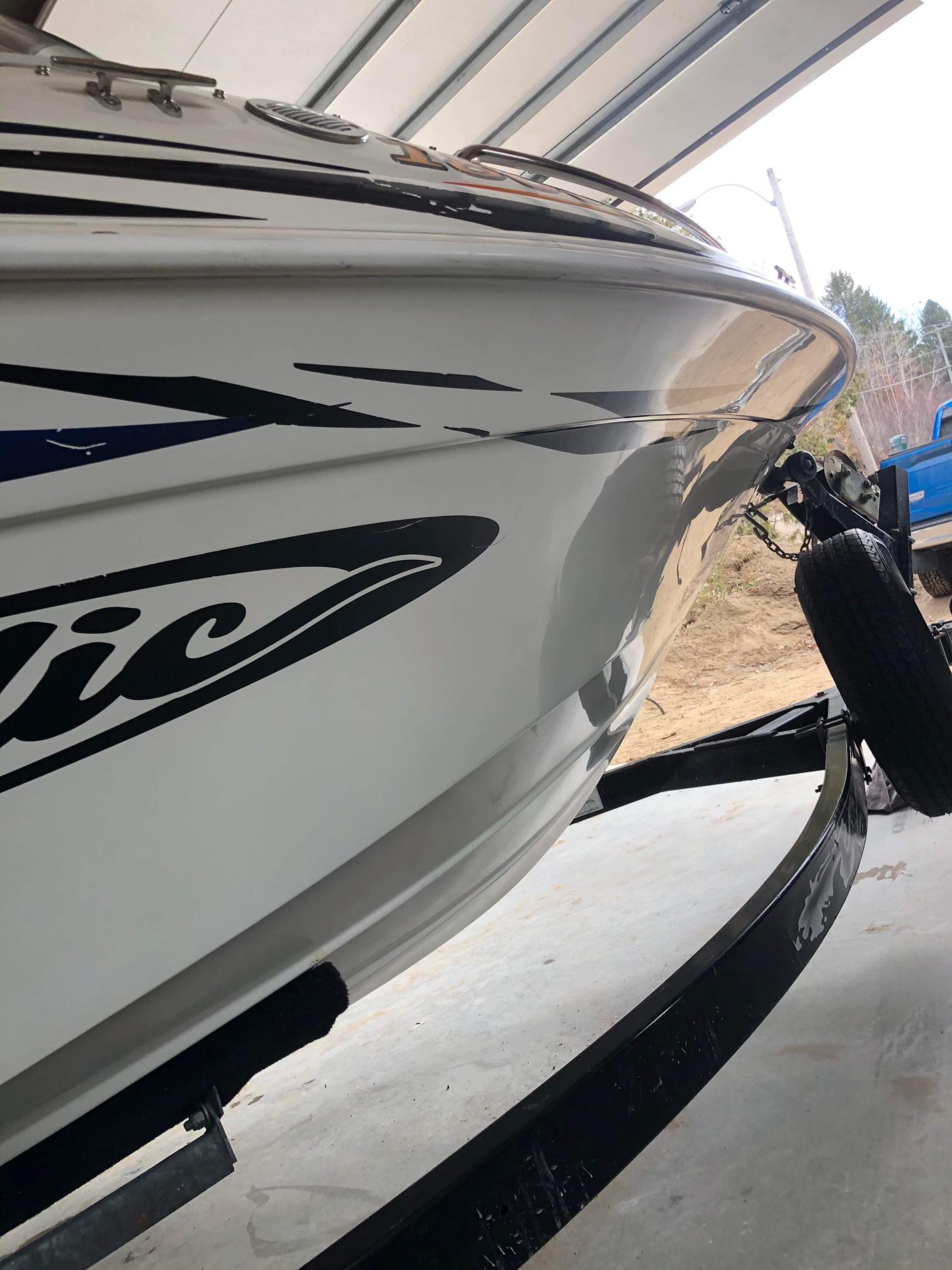 Un bateau blanc est garé dans un garage avec un camion bleu en arrière-plan.