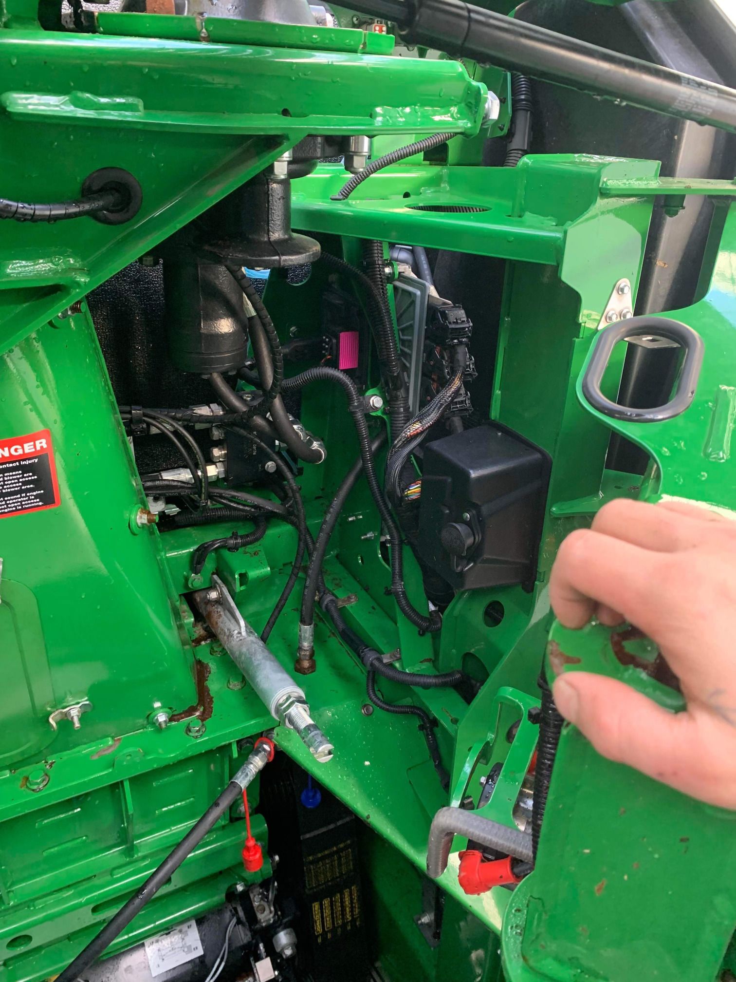 Une personne travaille sur le moteur d’un tracteur vert.