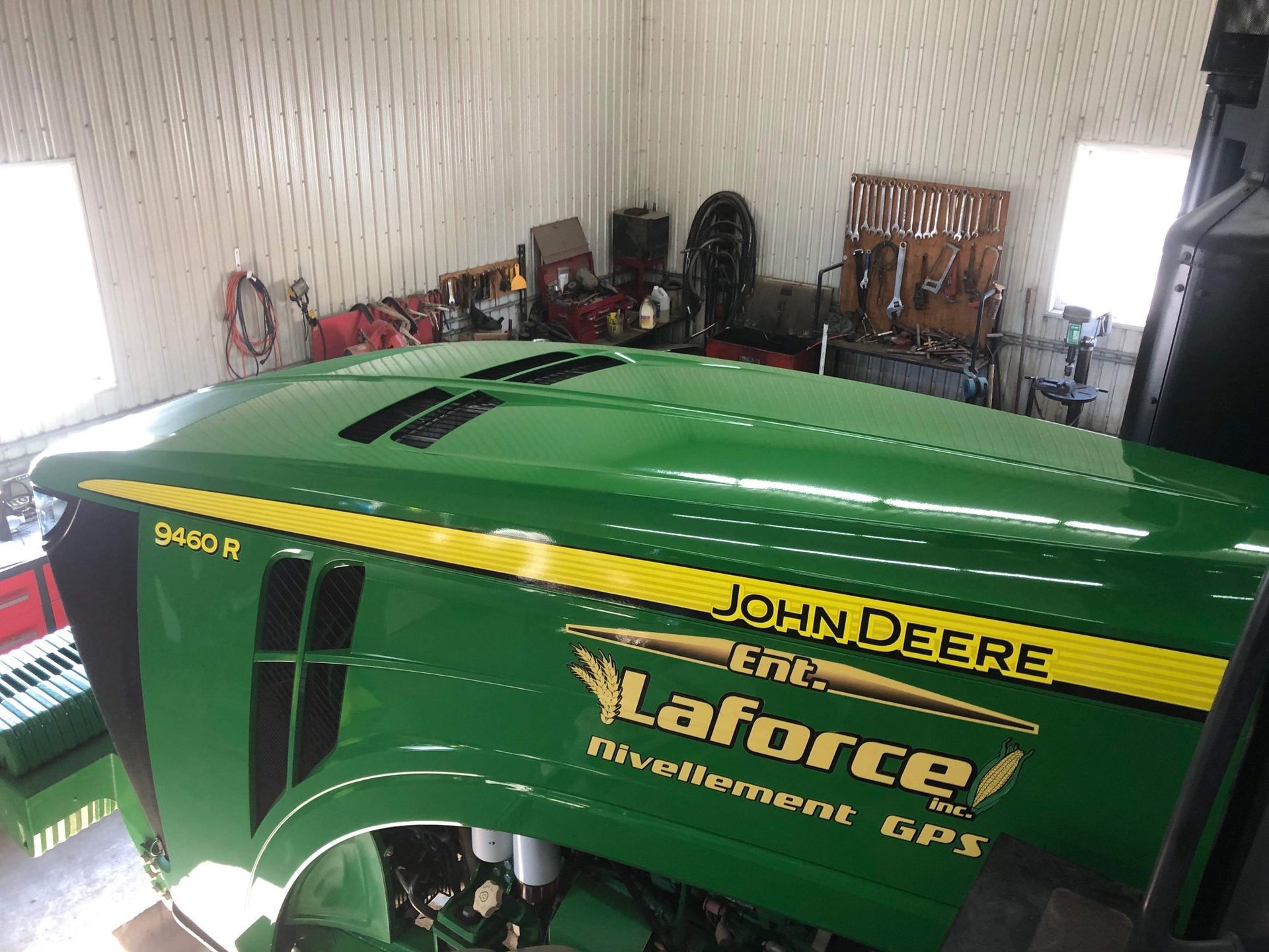 Un tracteur John Deere vert est assis dans un garage.