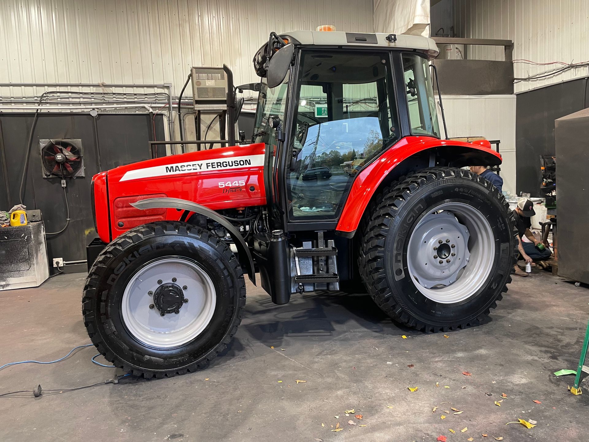 Un tracteur rouge est garé dans un garage.