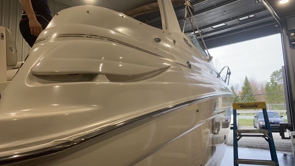 Un bateau blanc est assis dans un garage à côté d’une échelle.