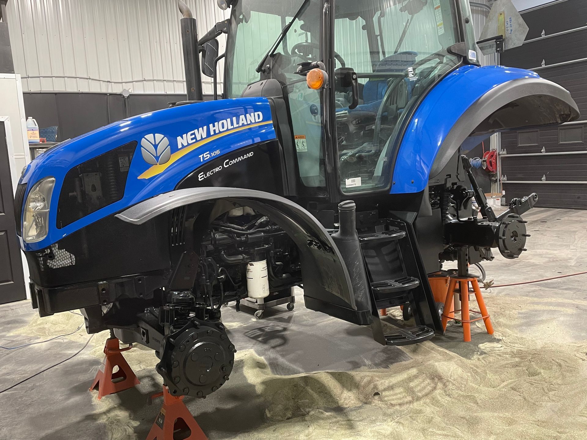 Un tracteur New Holland bleu est en réparation dans un garage.