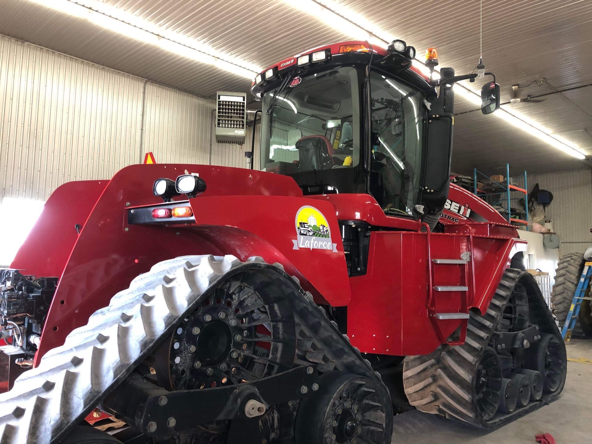 Un tracteur rouge aux chenilles noires est garé dans un garage.