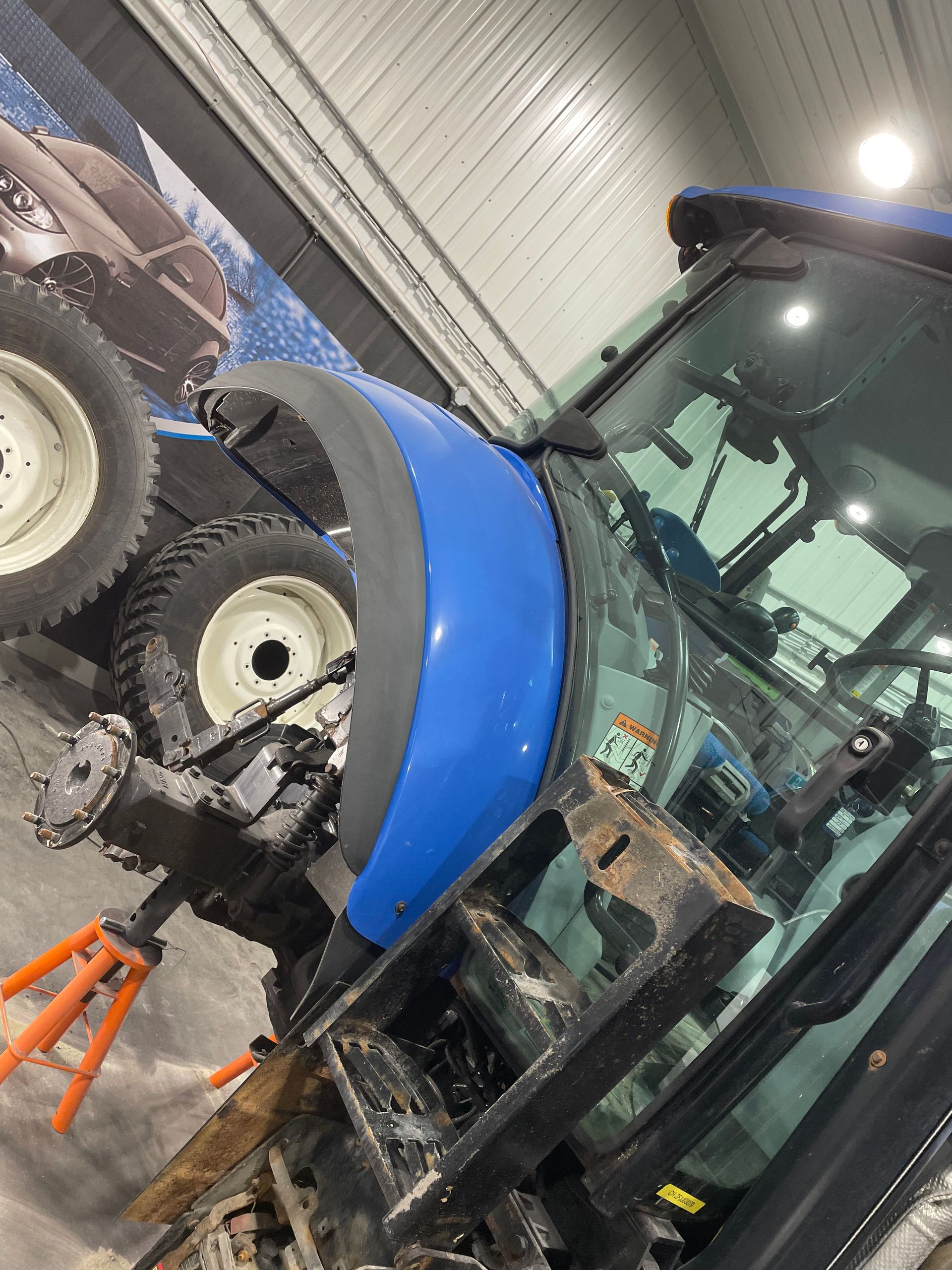 Un tracteur bleu est en travaux dans un garage.