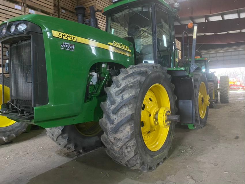 Un tracteur John Deere vert et jaune est garé dans un garage.