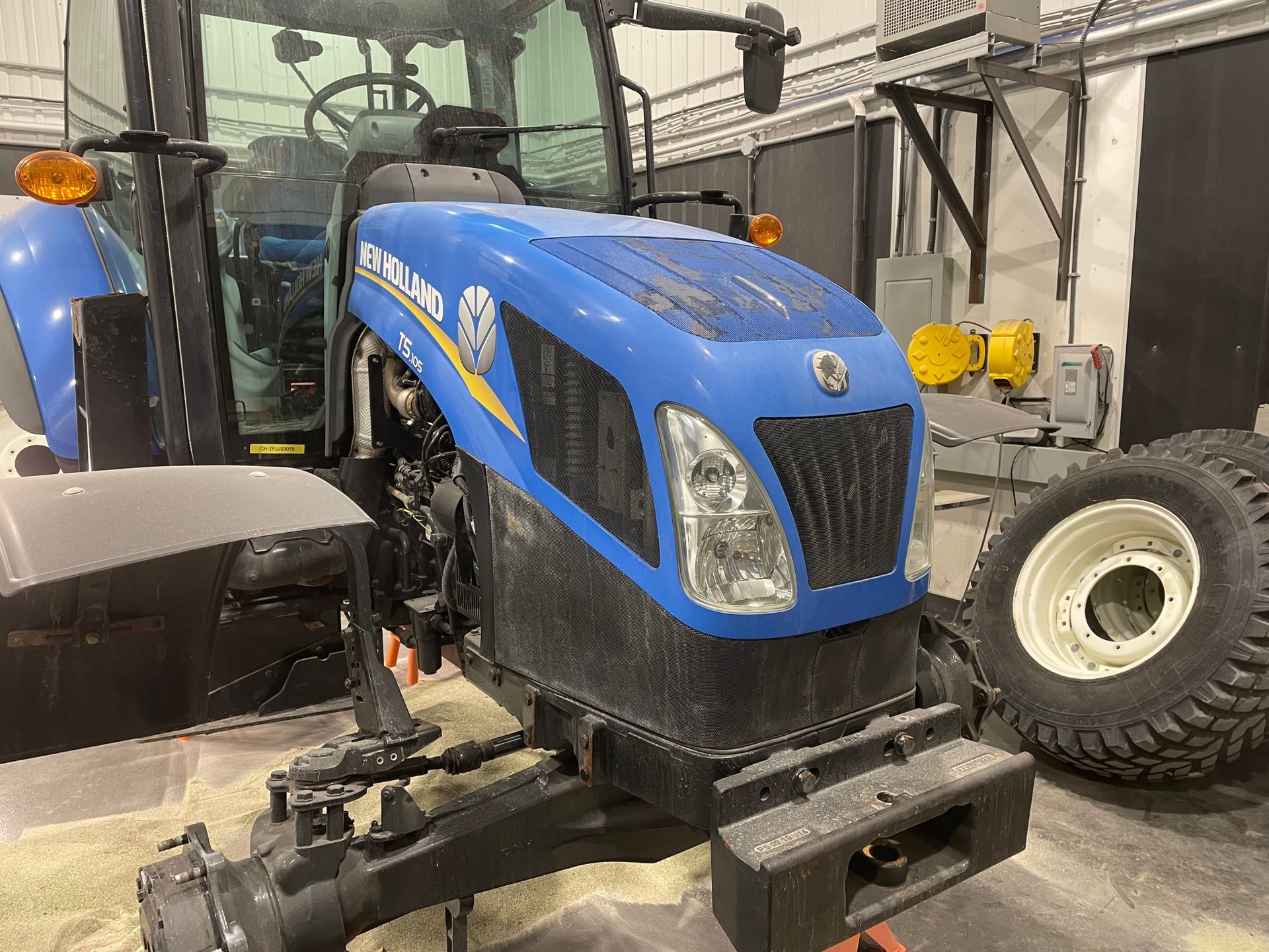 Un tracteur bleu et noir est garé dans un garage.