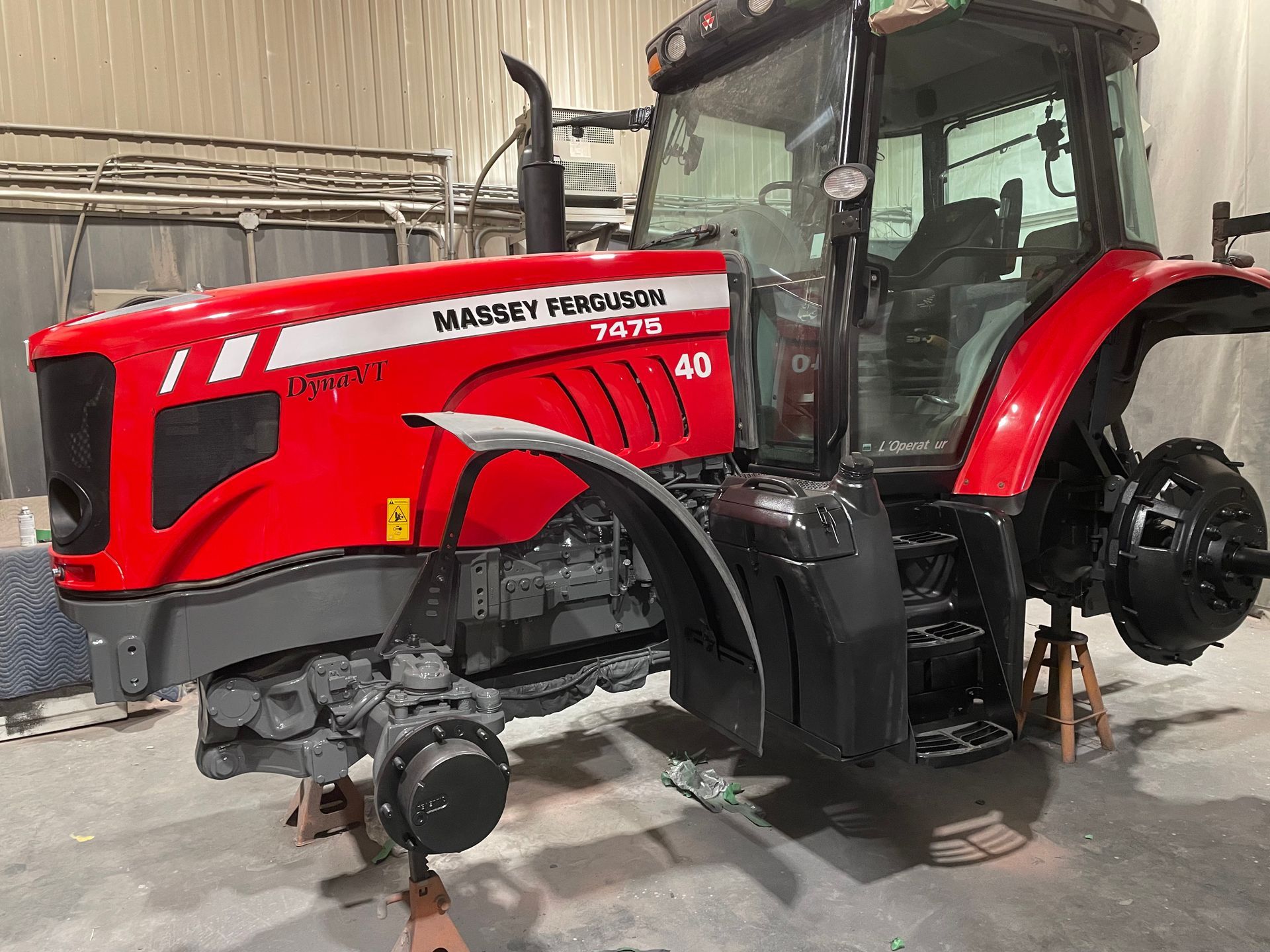 Un tracteur rouge et noir est assis dans un garage.
