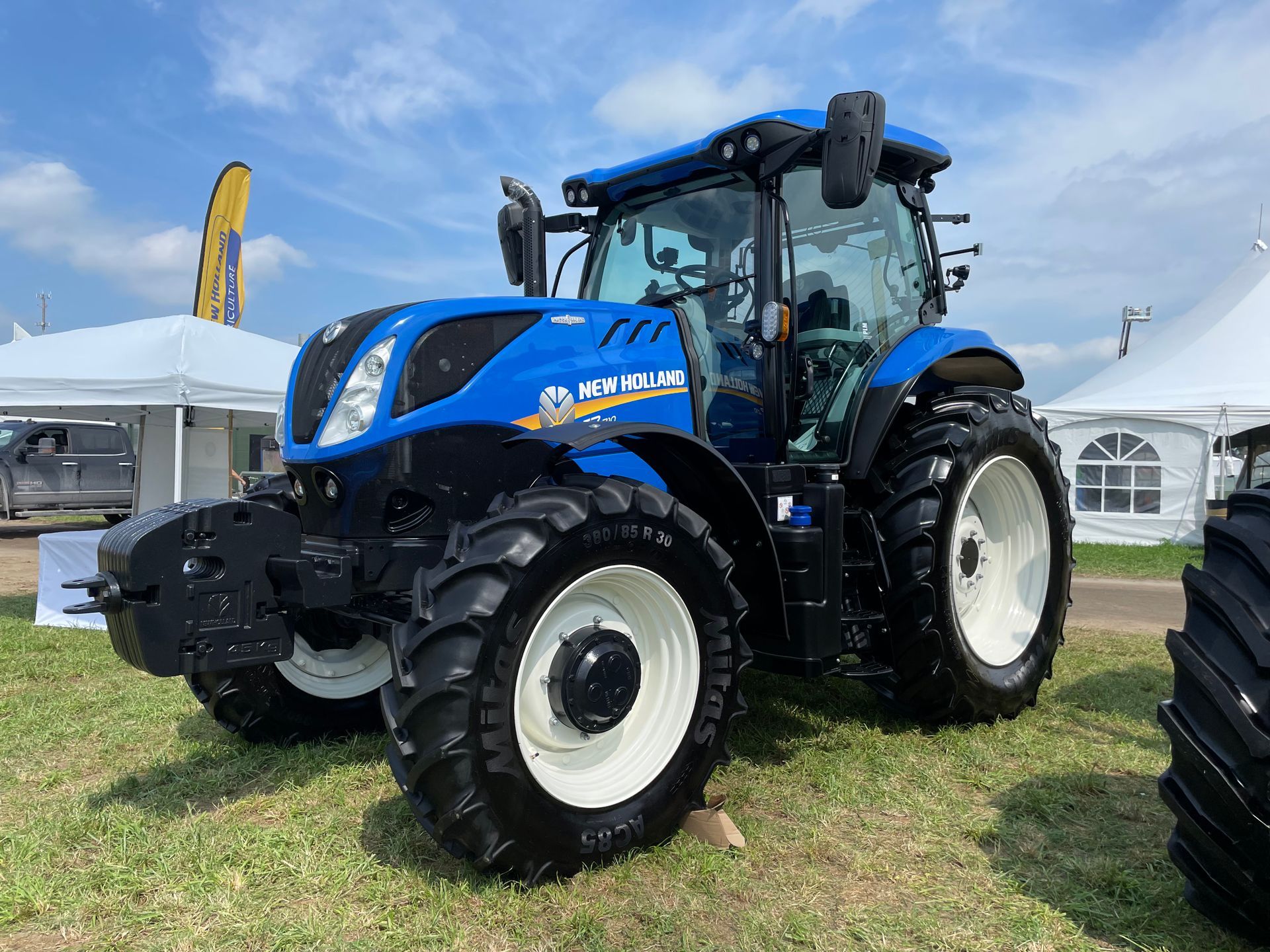 Un tracteur bleu et blanc est garé dans un champ herbeux.