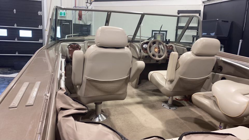 L'intérieur d'un bateau avec des sièges beiges et un volant.