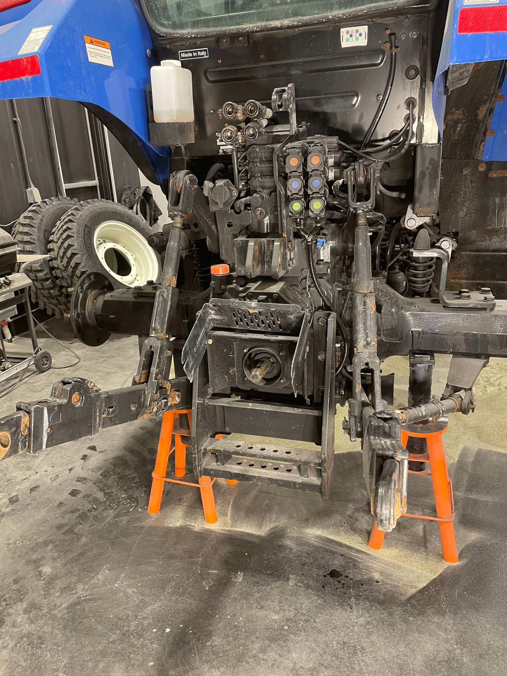 Un tracteur est posé sur une paire de supports orange dans un garage.