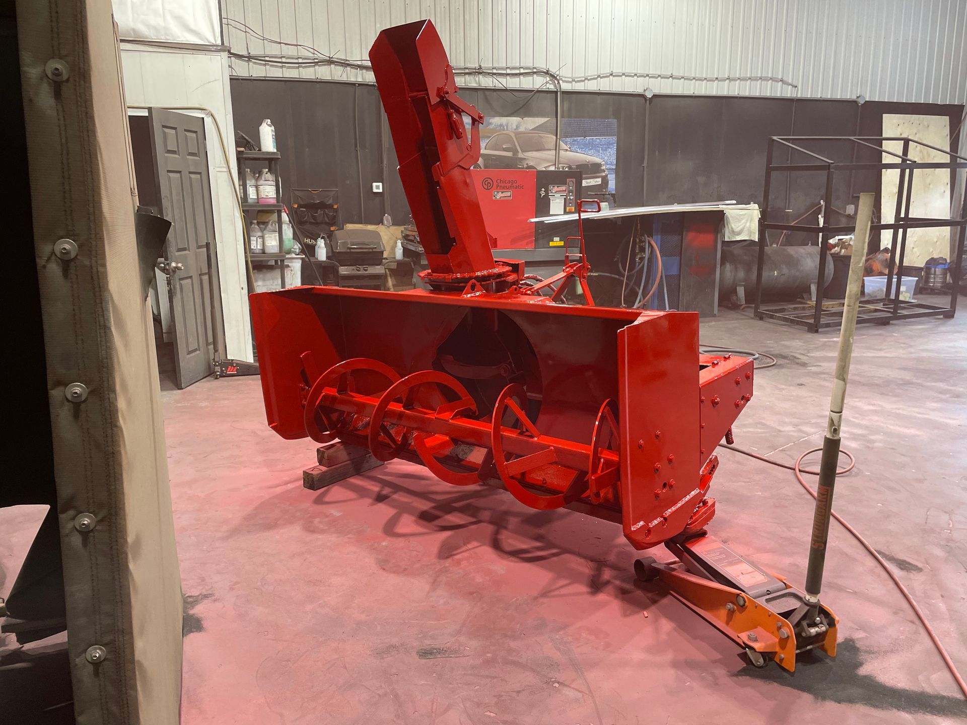 Une souffleuse à neige rouge est peinte en rouge dans un garage.